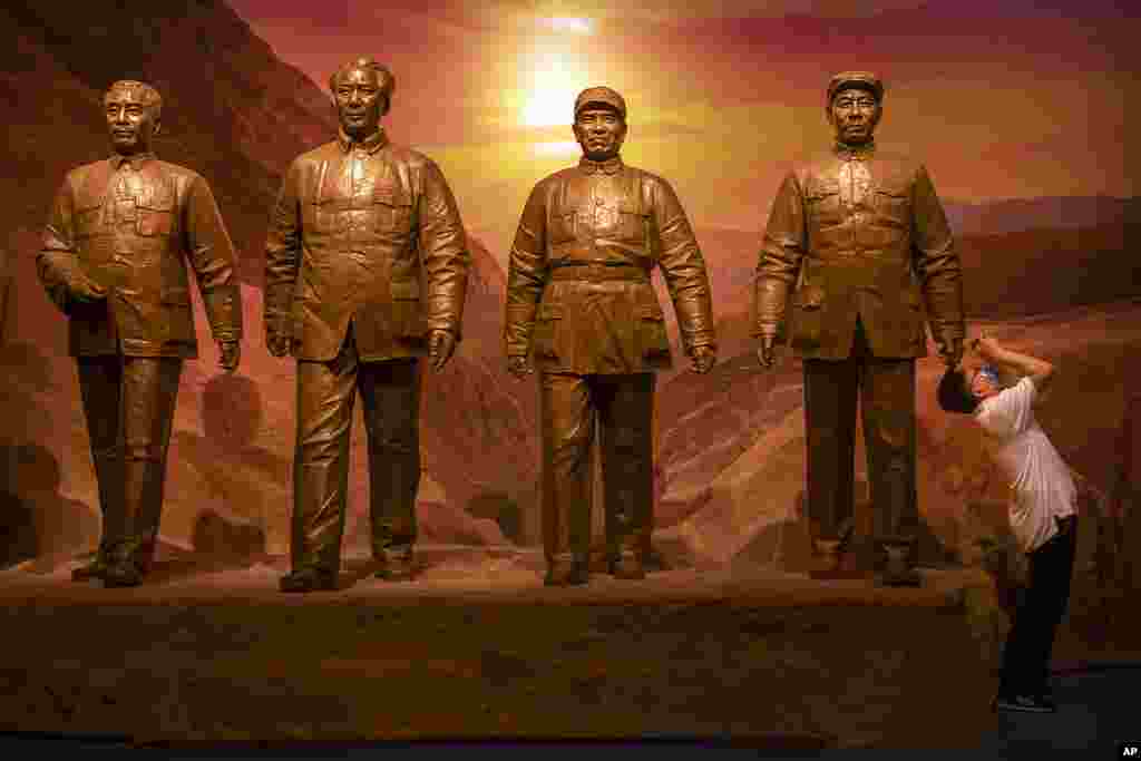 A visitor takes a photo of an exhibit near a statue of Chinese leader Mao Zedong, 2nd from left, and other Communist Party figures at the newly-completed Museum of the Communist Party of China in Beijing.