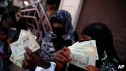 FILE - Yemeni women display paper currency in Sanaa, Yemen. 