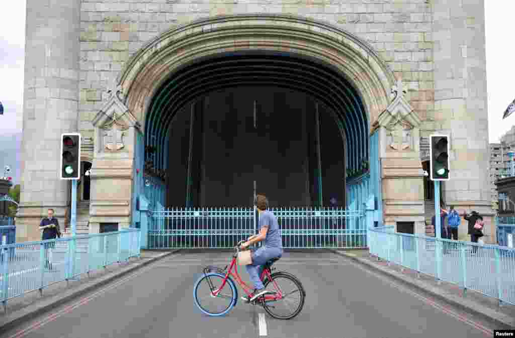 A cyclist looks towards Tower Bridge while it is stuck in the open position, due to a technical fault, in London, Aug. 9, 2021.