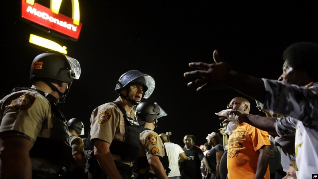 FILE - Officers and protesters face off along West Florissant Avenue in Ferguson, Mo., Aug. 10, 2015. The city and the U.S. Justice Department have reached an agreement over police reform.