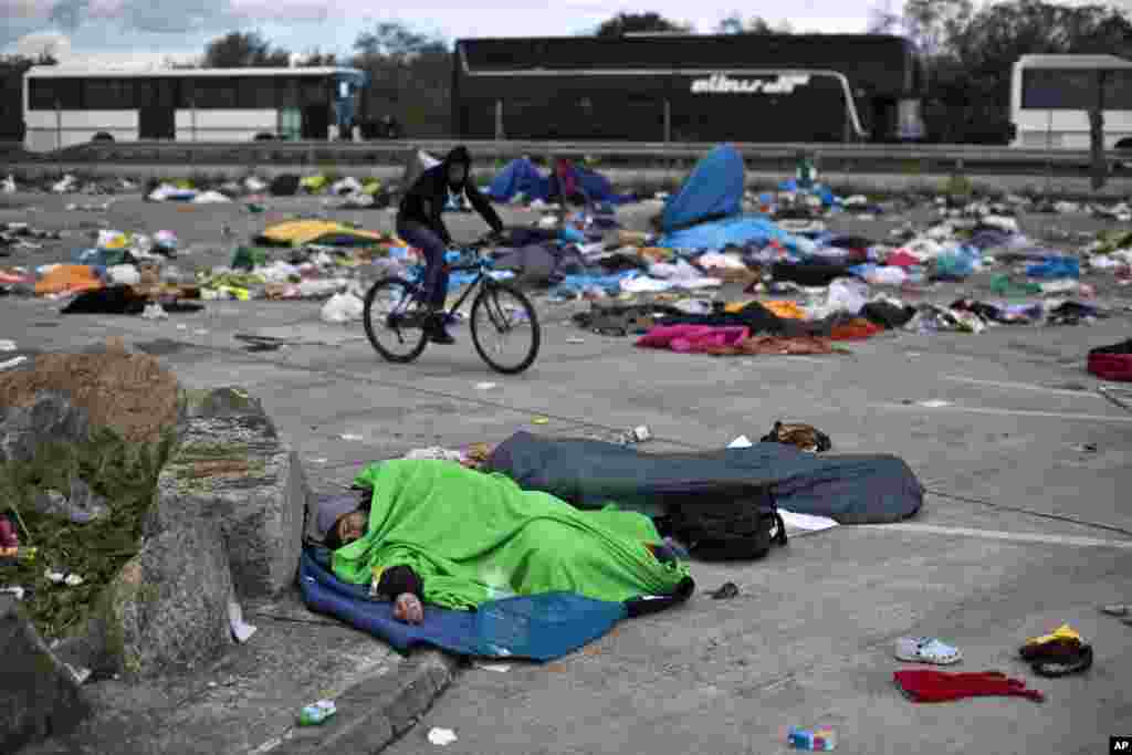 A man sleeps in a parking lot as buses organized by the Austrian government line up in Hegyeshalom, Hungary, Sept. 6, 2015.