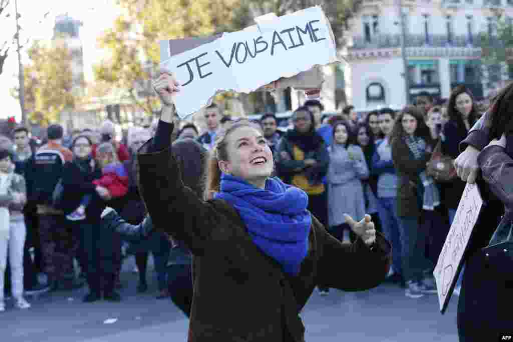 A woman holds a sign reading 'I love you' as people gather at the Place de la Republique in Paris, on Nov. 15, 2015, two days after a series of deadly attacks.