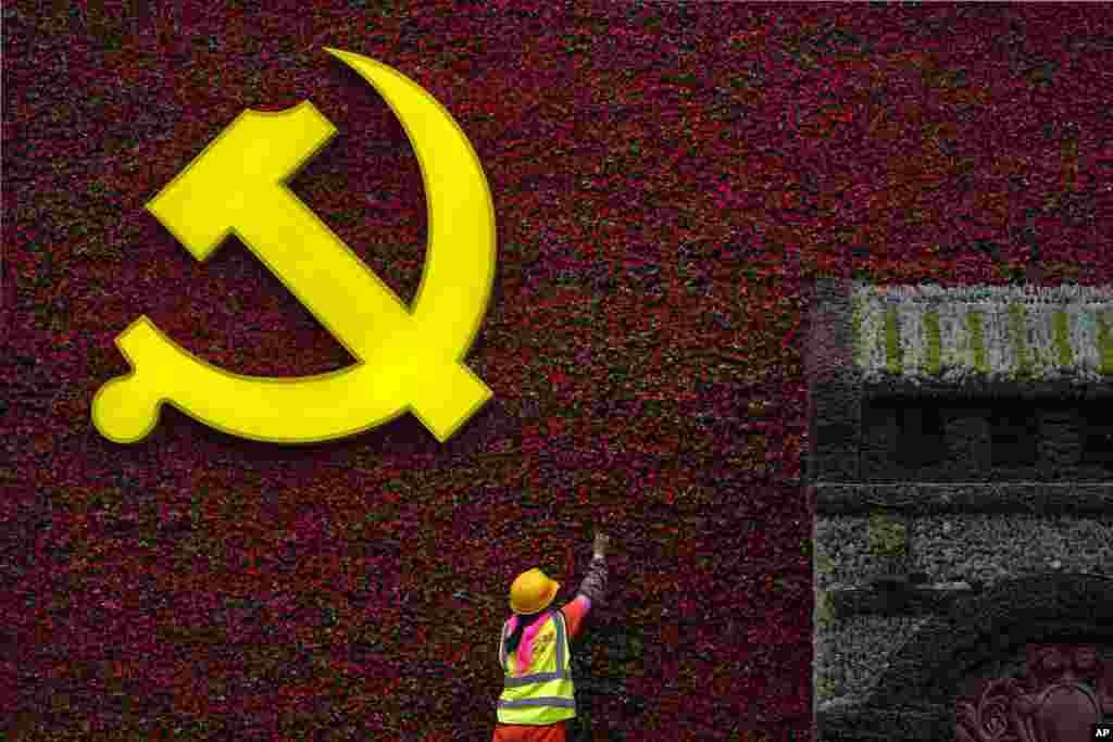 A worker installs a flag-shaped flowers decoration with a Communist Party&#39;s logo in Beijing, China.