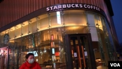 一名戴口罩的女士路过星巴克在北京的一家门店。（2020年2月20日）