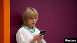 一名中国女子在街上使用苹果手机。（路透社2023年9月27日）