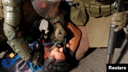 A policeman hits a detained demonstrator in the face during a protest against Chile's government in Santiago, Nov. 20, 2019.