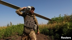 Український військовослужбовець несе розвідувальний дрон на стартову позицію поблизу лінії фронту в Донецькій області. Липень 2023 року. Фото: Reuters/Sofiia Gatilova