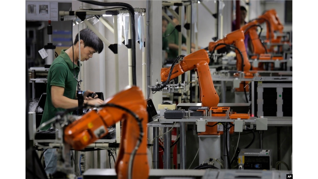 An employee works amid robot arms at a technology factory in the southern Chinese industrial boomtown of Shenzhen, Aug. 21, 2015. Chinese officials are calling on the U.S. to act responsibly on matters of taxation.