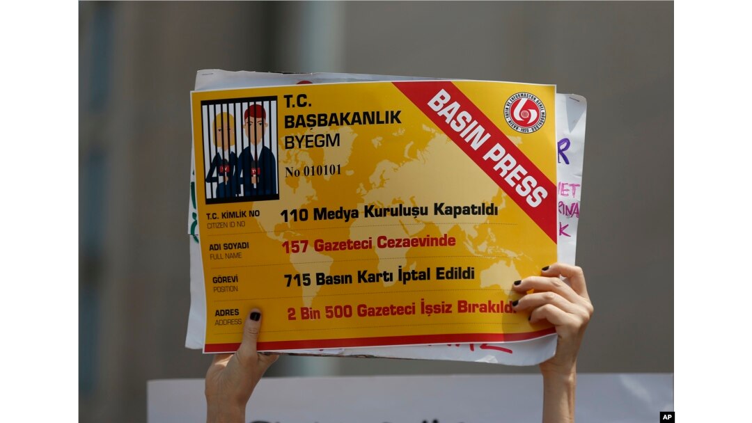 An activist holds a placard, made to look like a press card, that reads " 110 media organizations closed,157 journalists jailed, 715 press cards cancelled, 2.500 journalists fired " outside the court in Istanbul, July 28, 2017.