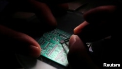 资料照：北京紫光集团研究中心的一名研发人员正在一片半导体接口板上工作。（2016年2月29日）