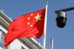 北京街头飘扬的一面中国国旗旁的一个监控摄像头。（2021年11月25日）