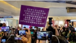 7月19日下午有区议员在元朗Yoho Mall呼吁市民关注7-21袭击事件一周年，有人高呼”光复香港、时代革命”口号，警方高举紫色旗警告违反国安法 (美国之音/汤惠芸)