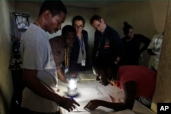 Members of the European Union Election Observation Mission, behind, observe electoral workers count ballots at a polling station at the end of the national elections in Port-au-Prince, Haiti, Oct. 25, 2015.