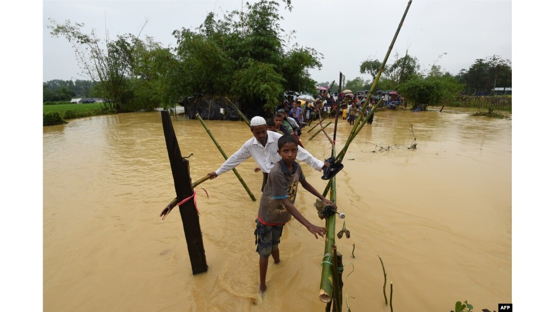 FILE - Rohingya refugees cross floodwaters at Thangkhali refugee camp in Bangladesh's Cox's Bazar district, Sept. 17, 2017.