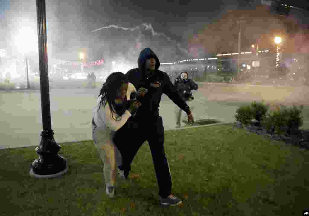 Người biểu tình bỏ chạy sau khi cản sát bắn hơi cay vào đám đông bạo động ở Ferguson, Missouri, ngày 24/11/2014.
