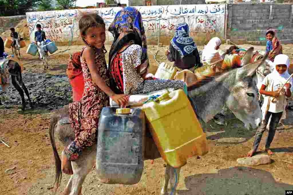 Children riding on donkeys queue to fill their jerrycans with water from a cistern at a make-shift camp for the internally displaced in Yemen's northern Hajjah province amid extreme heatwave and severe water shortage.