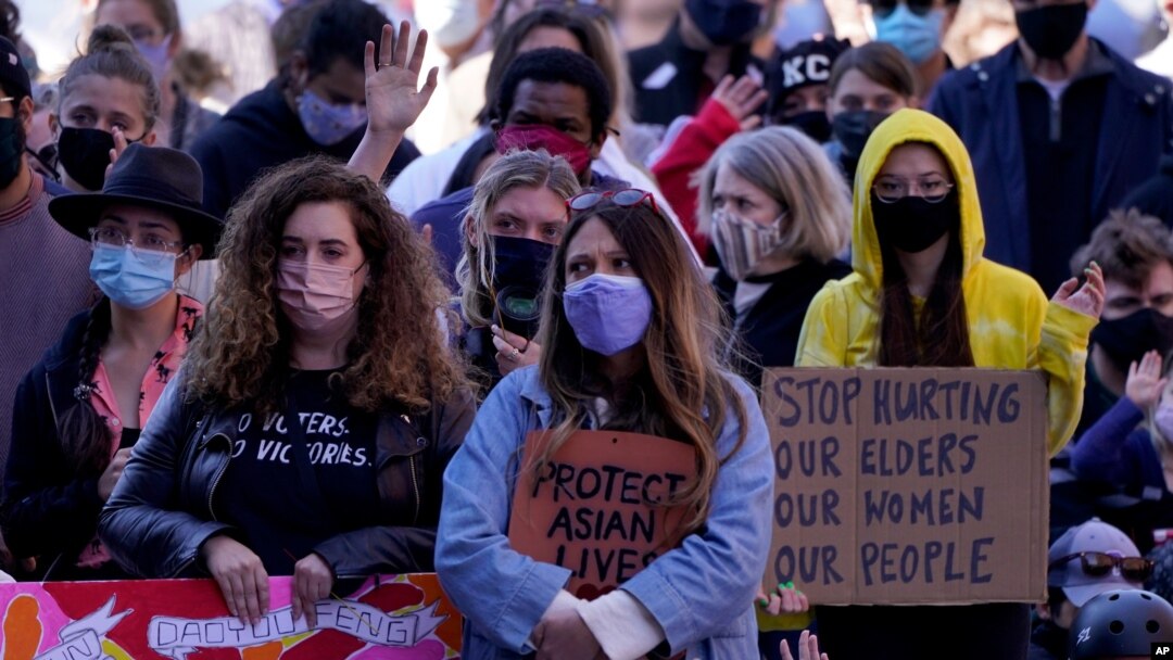 People hold signs of support at a memorial to remember the victims of the Atlanta area massage parlors shootings during a memorial in Kansas City, Mo., March 28, 2021. 