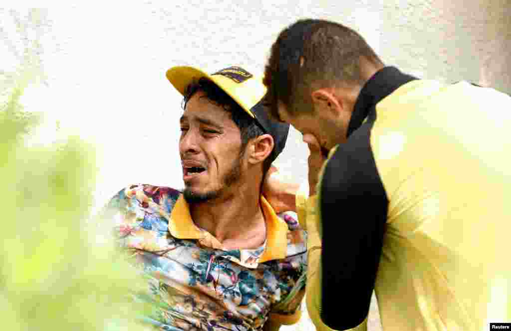 Relatives of Tunisian migrants, who drowned when their boat sank, react as they leave a hospital morgue after identifying the bodies of their family members, in Sfax, Tunisia.