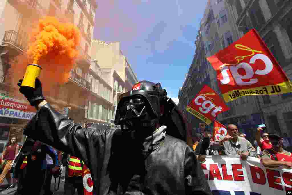 A steelworker from the ArcelorMittal steel plant in Fos-sur-Mer wearing a mask of Darth Vader, burns flares during a demonstration in Marseille, southern France.