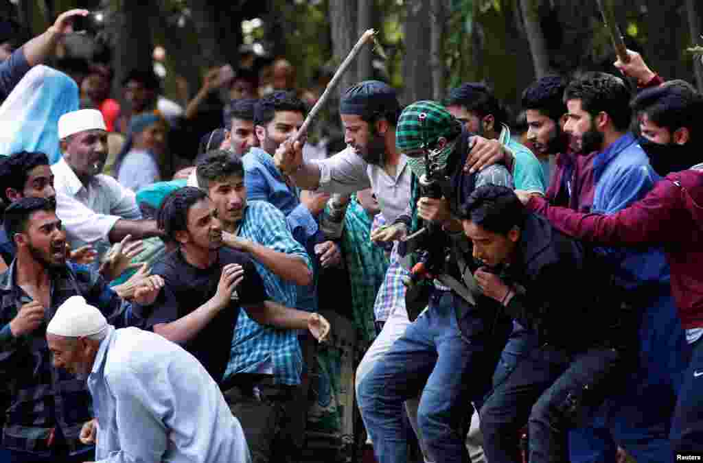 People run during a funeral of Suhail Ahmad Dar, a suspected militant, who according to local media was killed in a gun battle with security forces, in south Kashmir's Kulgam district, India.