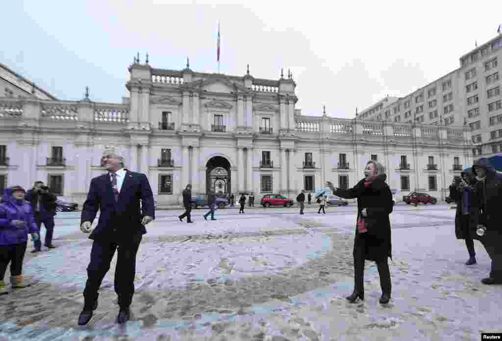 Chile's President Sebastian Pinera is hit by a snowball tossed at him by his wife, first lady Cecilia Morel outside of the government palace after an unusual snowfall in Santiago, June 11, 2018.