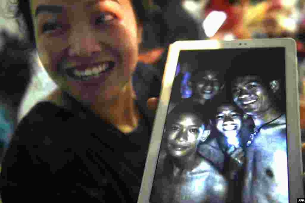 A happy family member shows the latest picture of the missing boys taken by rescue divers inside Tham Luang cave when all members of children's football team and their coach were found alive at Khun Nam Nang Non Forest Park in the Mae Sai district of Chiang Rai province, northern Thailand. Twelve boys and their football coach trapped in a flooded cave for nine days were "found safe."