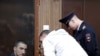 Defendant Pavel Ustinov, accused of using violence against an officer of Russia's National Guard during an unauthorized rally to demand free elections, listens to a lawyer during a court hearing in Moscow, Sept. 16, 2019.