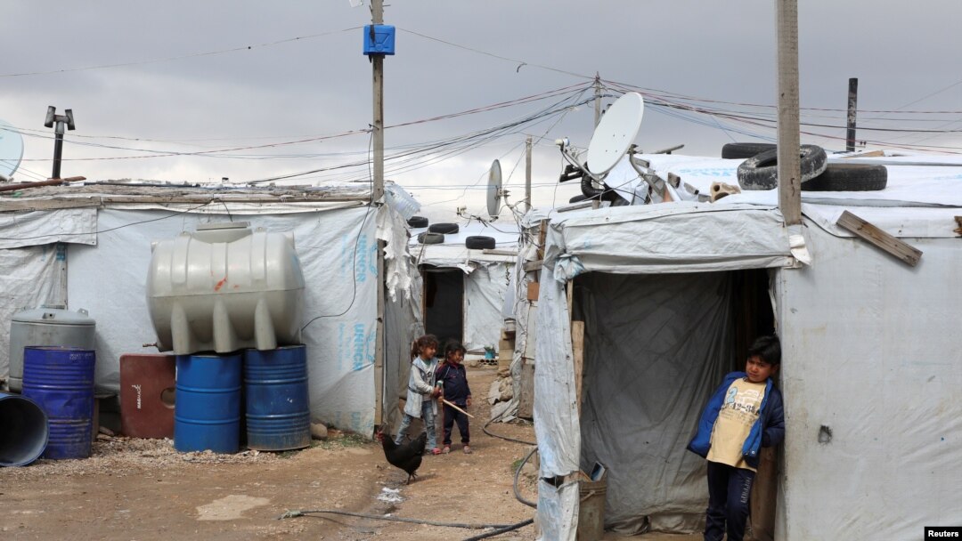 FILE - A Syrian refugee boy stands in front of a tent at an informal tented settlement in the Bekaa valley, Lebanon, March 12, 2021. 