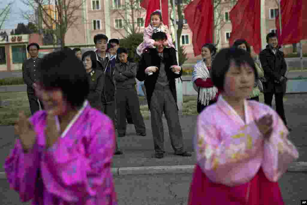 2013年4月15日,人们在平壤室内体育馆前观看民族舞蹈表演,一个小男孩坐在爸爸的肩膀上捂住爸爸的眼睛。