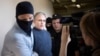 Paul Whelan, a former U.S. Marine, second left, who was arrested for alleged spying in Moscow at the end of 2018, speaks to a journalist as he escorted by Federal Security Service officers to a court room in Moscow, Russia, Aug. 23, 2019. 
