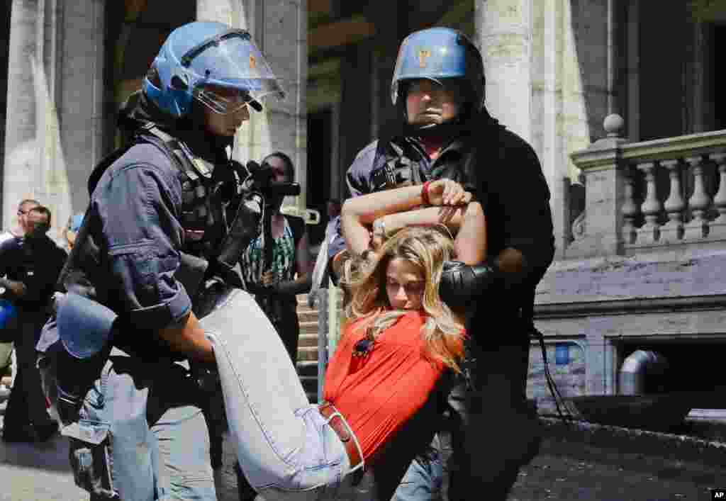 A protester is dragged away by Italian police outside the Ministry of Transport in Rome, Italy. Dozens of protesters chained themselves to the steps in a demonstration against the government's hard-line immigration policy.