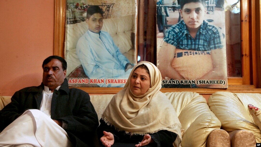 Pakistani mother Shahana with her husband Ajoon Khan sit next to photos of their son Asfand Khan, who was killed in a 2014 assault by Pakistani Taliban militants on an army public school, in Peshawar, Pakistan, Dec. 29, 2021.