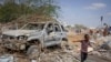 Um rapaz passa pelos destroços de veículo destruído em ataque do grupo extremista al-Shaba à polícia e postos de controlo na periferia da capital Mogadíscio, Somália, 16 de Fevereiro de 2022). (AP Photo/Farah Abdi Warsameh)al-Shabab