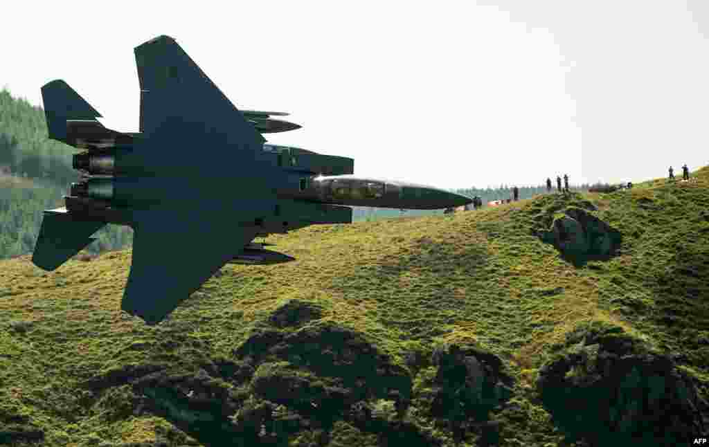 Military aircraft enthusiasts watch as a U.S. Air Force (USAF) F-15 fighter jet travels at a low altitude through the 'Mach Loop' series of valleys near Dolgellau, north Wales.