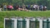 ARCHIVO: Migrantes hablan con funcionarios en un camino cerca del río Grande después de cruzar la frontera desde México a Texas el 11 de mayo de 2023.