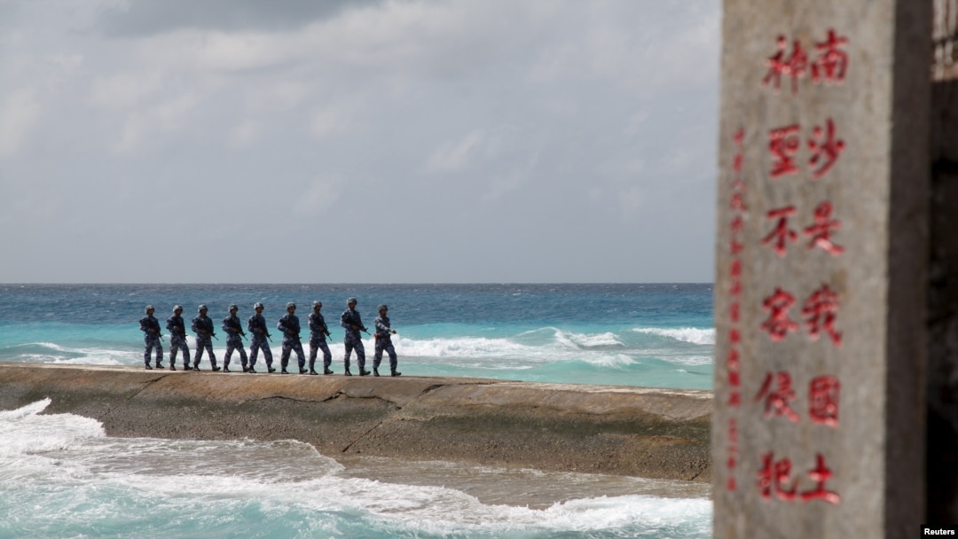FILE - Soldiers of China's People's Liberation Army (PLA) patrol near a sign in the Spratly Islands, known in China as the Nansha Islands, Feb. 9, 2016.