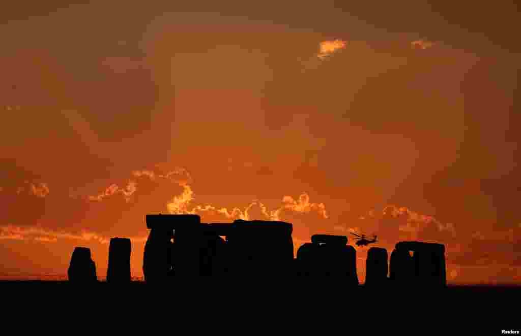 A helicopter flies behind the Stonehenge stone circle during sunset in southwest Britain, July 26, 2018.