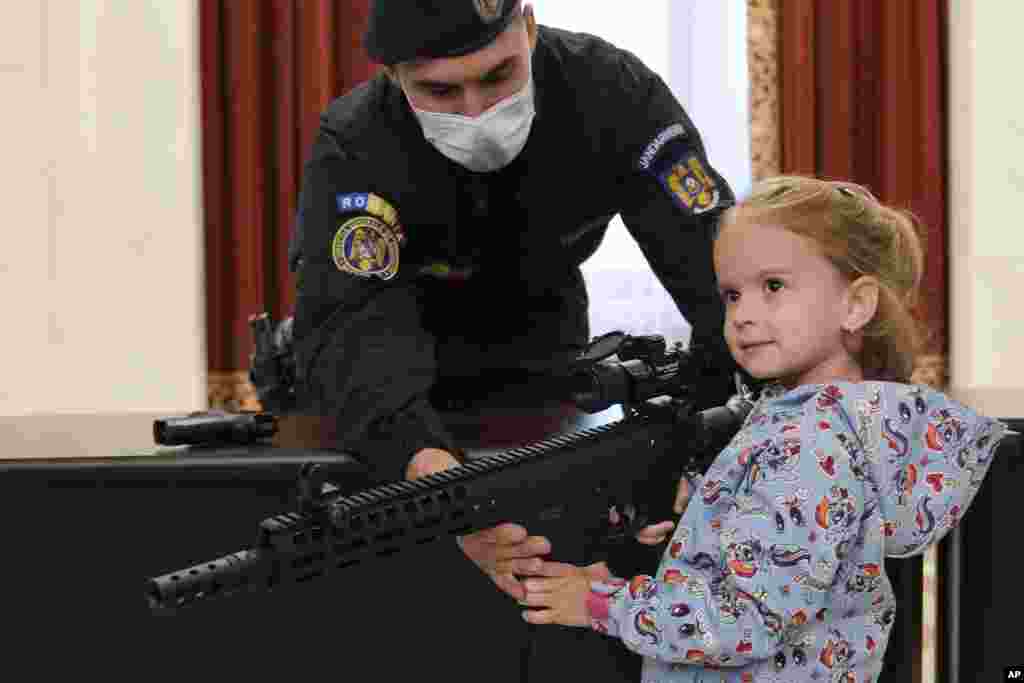 A girl poses with a weapon at a stand set up by Romania's gendarmerie at the Palace of the Parliament, on International Children's Day in Bucharest.