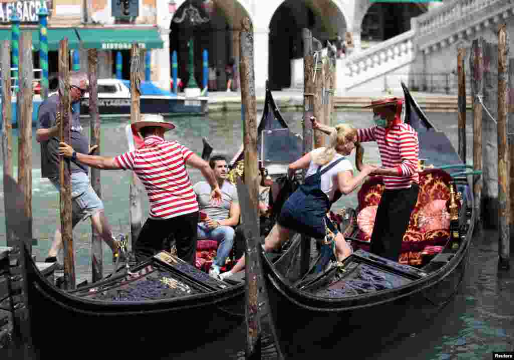 Gondoliers help tourists to get on the gondolas, as the region of Veneto becomes a "white zone", following a relaxation of COVID-19 restrictions with only masks and social distancing required, in Venice, Italy.