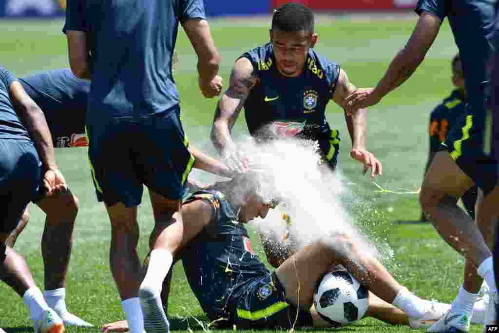 Brazil's Neymar (not in frame) and Gabriel Jesus (C) break an egg on the head of teammate Philippe Coutinho as they celebrate his birthday during a training session at Sochi Municipal Stadium in Sochi, ahead of the Russia 2018 World Cup football tournament.