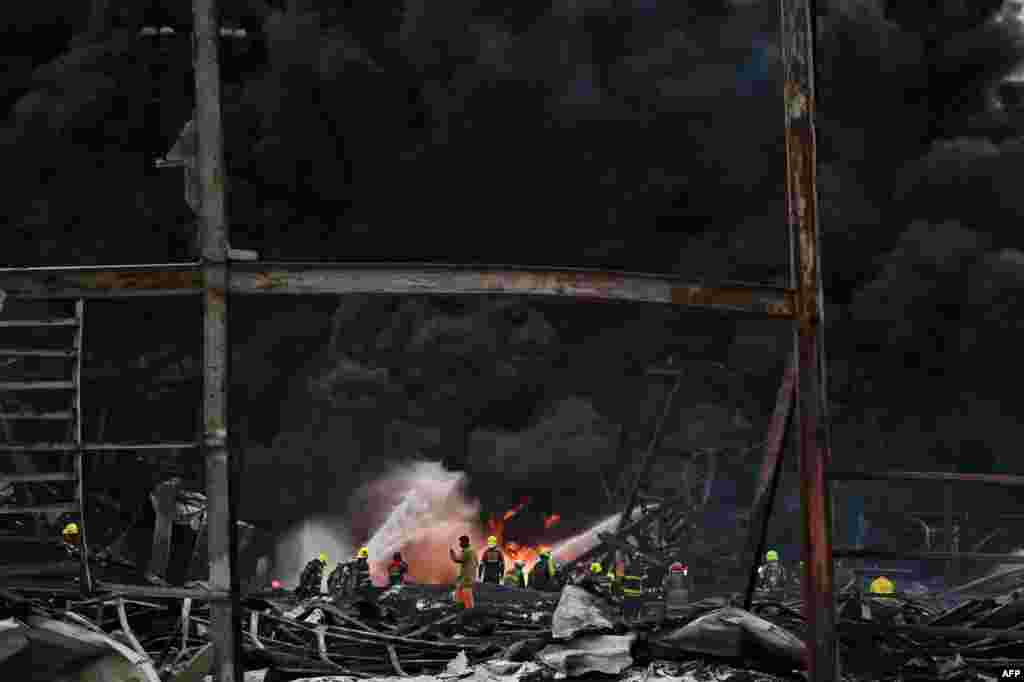 Firefighters work at the site of an explosion and fire at a plastics factory on the outskirts of Bangkok, Thailand