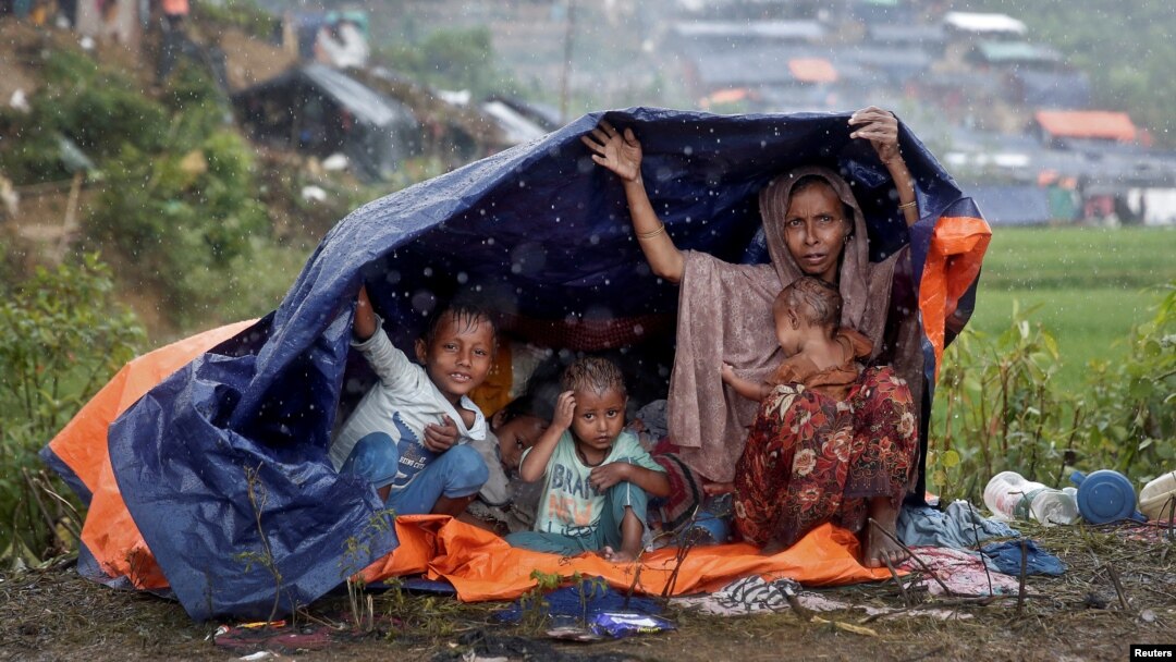 FILE - Rohingya refugees shelter from the rain in a camp in Cox's Bazar, Bangladesh, Sept. 17, 2017.