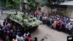 孟加拉國軍隊的裝甲車開過，路旁是記者（2016年7月2日）