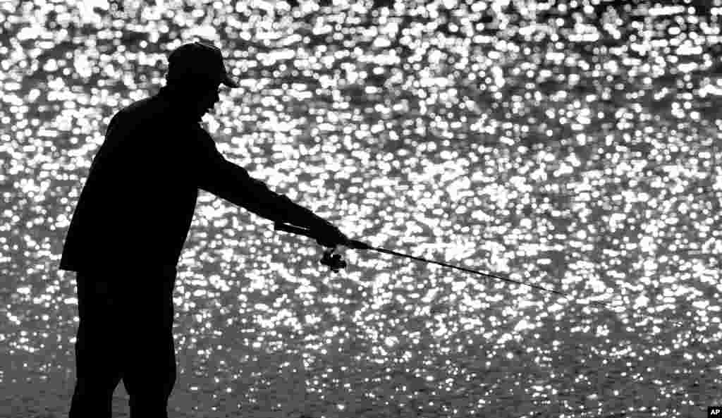 Minh Quang fishes off a dock at Gray's Lake Park in Des Moines, Iowa.
