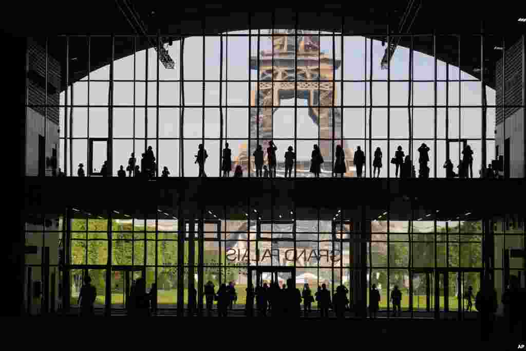 Visitors gather during a presentation visit of the "Grand Palais Ephemere", with the Eiffel Tower seeing outside, in Paris, France.