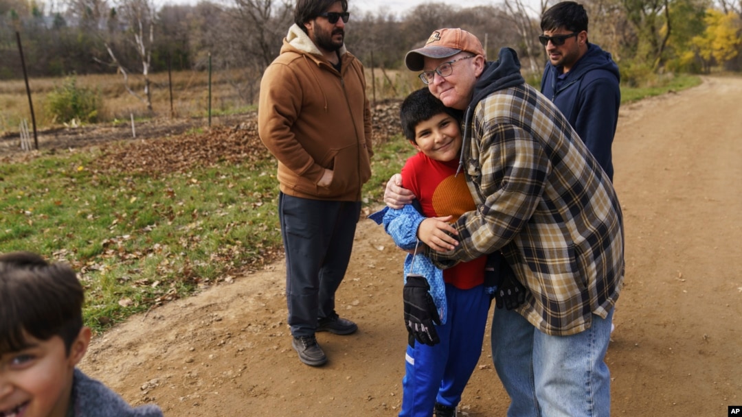Caroline Clarin, right, hugs Haiwad Massoodi on a visit by his father, Sami, rear left, and Sami Massoodi's cousin Ihsanullah Patan, right, and Patan's son, Ali, at her farm in Dalton, Minn.Oct. 30, 2021.