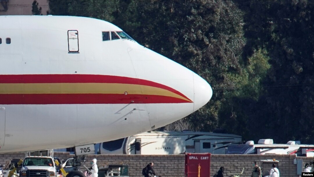 FILE - Women and children walk past personnel after arriving on an aircraft chartered by the U.S. to evacuate Americans from the Chinese city of Wuhan, at March Air Reserve Base in Riverside County, California, Jan. 29, 2020. 