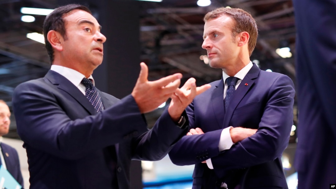 French President Emmanuel Macron listens to Carlos Ghosn, the CEO of French car maker Renault, left, at the Renault stand during an official visit at the Paris Motor Show, in Paris, France, Oct. 3, 2018.