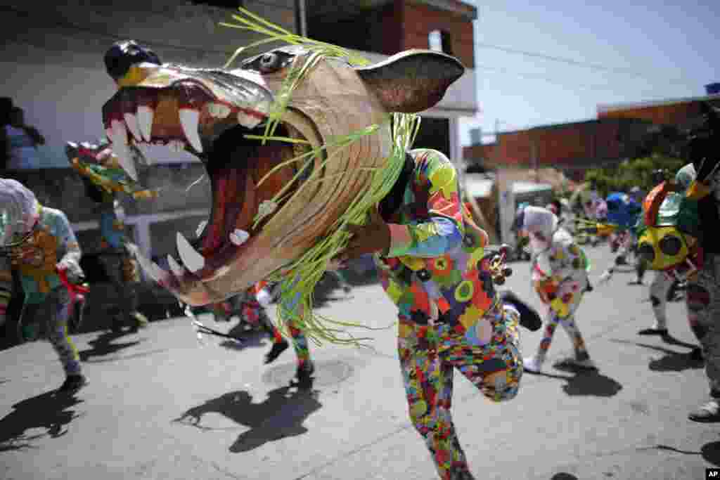 People dressed as a dancing devils with giant mask dance on a street, during a traditional celebration in Naiguata, Venezuela.