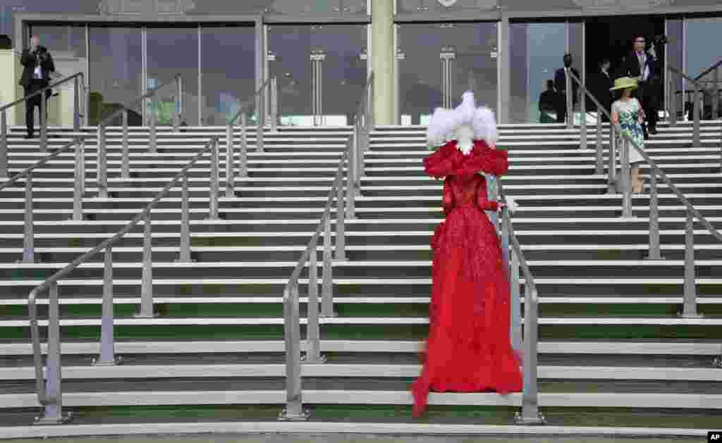 Debora Day in an ornate red outfit poses on the steps for photographers on the third day of the Royal Ascot horserace meeting, which is traditionally known as Ladies Day, at Ascot, England.